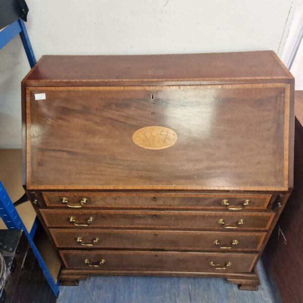 Front view of a vintage mahogany writing bureau with three drawers.