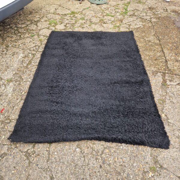 Black Ikea shag pile rug for living room comfort.