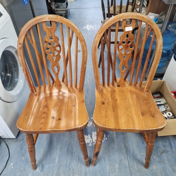 Pair of vintage wheelback dining chairs with wooden frames.