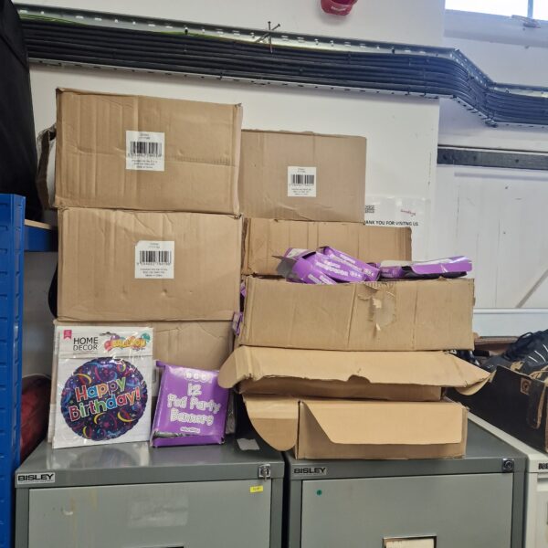 Stack of party supplies including birthday balloons and foil banners.