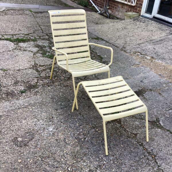 Vintage metal garden chair with footrest in a garden setting.