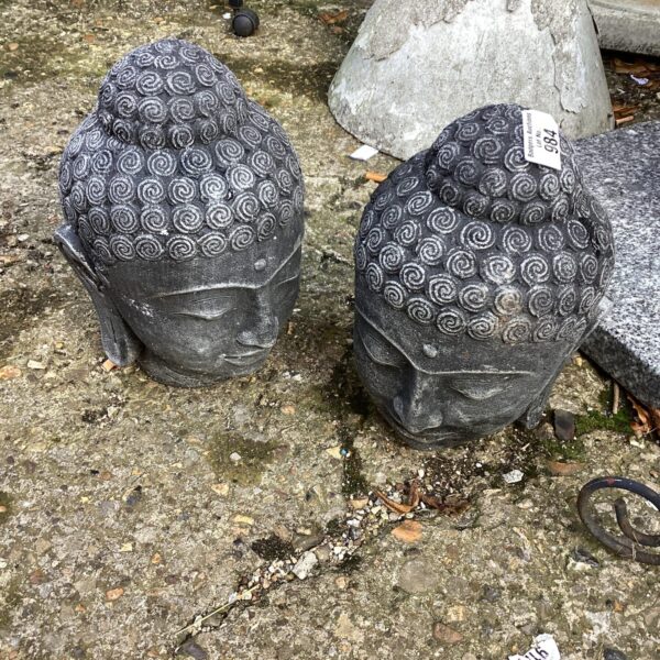 Weathered stone Buddha heads garden ornaments with moss growth.