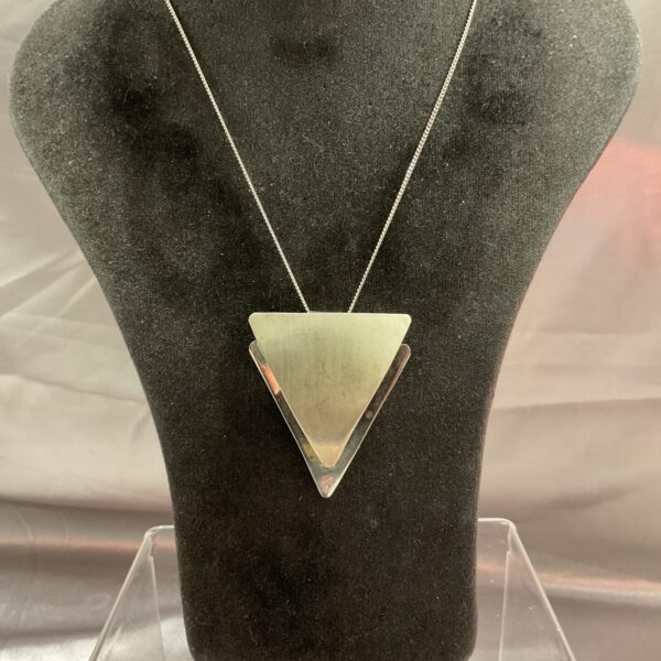Polished silver triangular pendant on a delicate chain necklace.