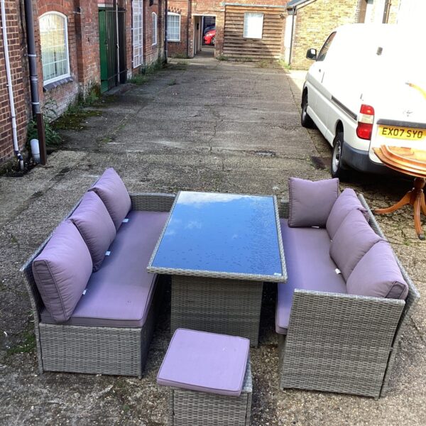 Rattan garden furniture set with comfortable cushions on a patio.