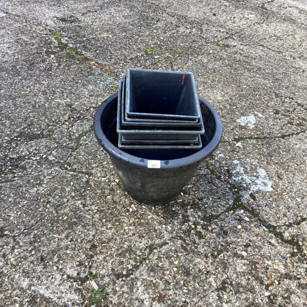 Dark grey plastic garden planters nested together for storage.