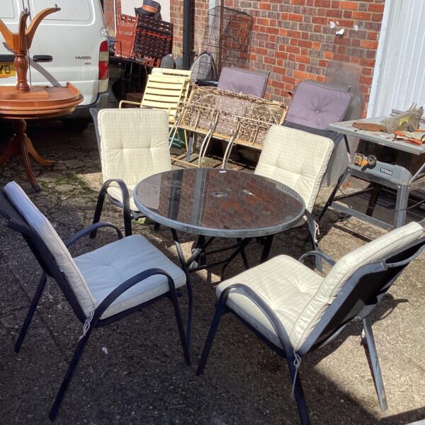 Metal garden patio set with table and four chairs on a patio.