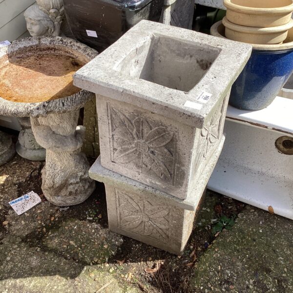 Pair of weathered square stone garden planters for outdoor use.