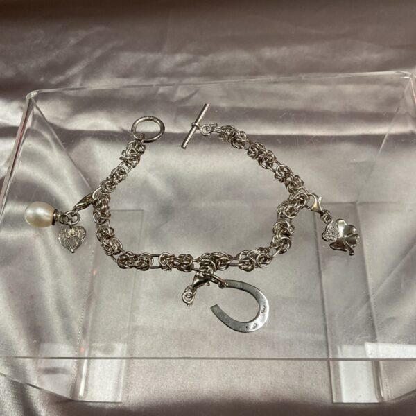 Vintage silver charm bracelet with heart, flower, and horseshoe charms.