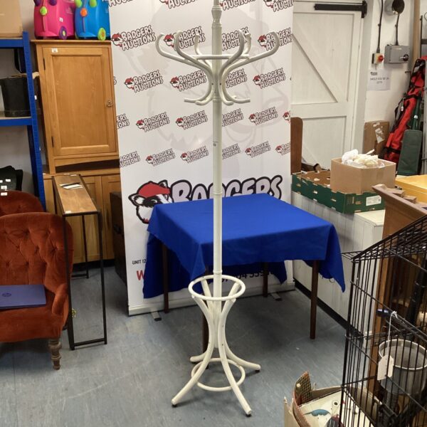 Vintage wooden coat stand with umbrella holder in a hallway.