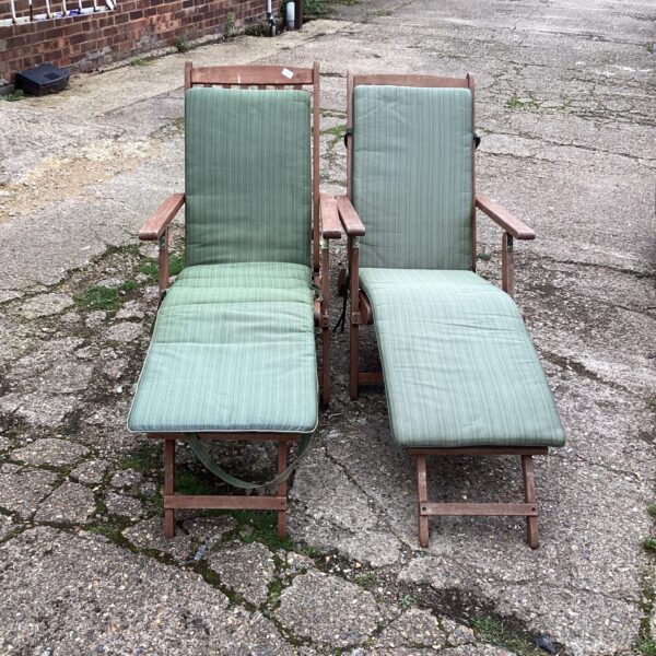 Two vintage teak garden chairs with reclining backs in a garden setting.