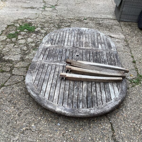 Large round teak garden table with slatted top, weathered finish.