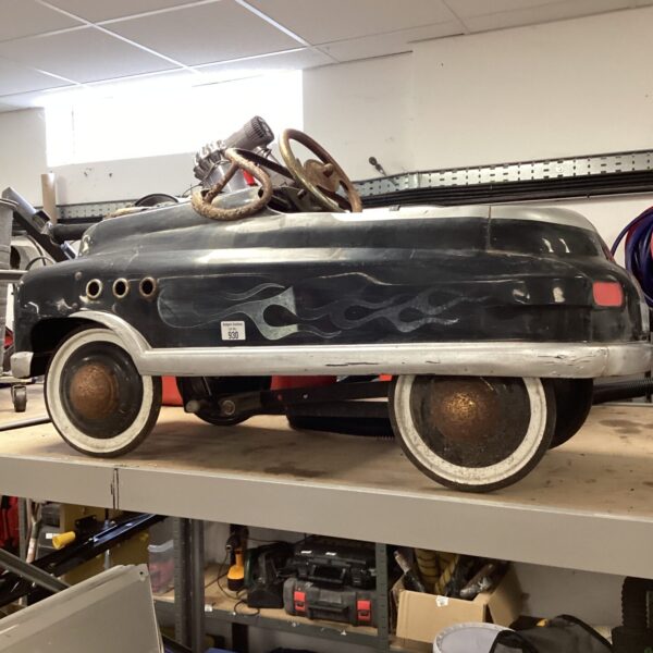 Vintage metal pedal car with weathered finish.