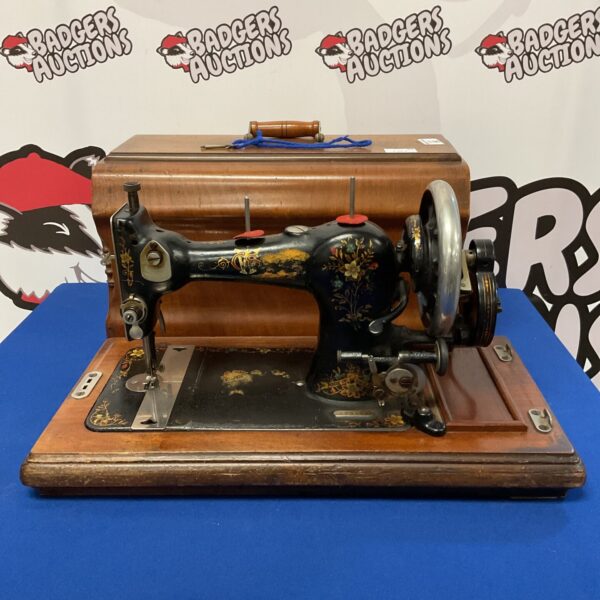 Antique hand crank sewing machine with wooden base.