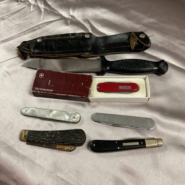 Vintage pocket knife collection with sheath knife displayed.