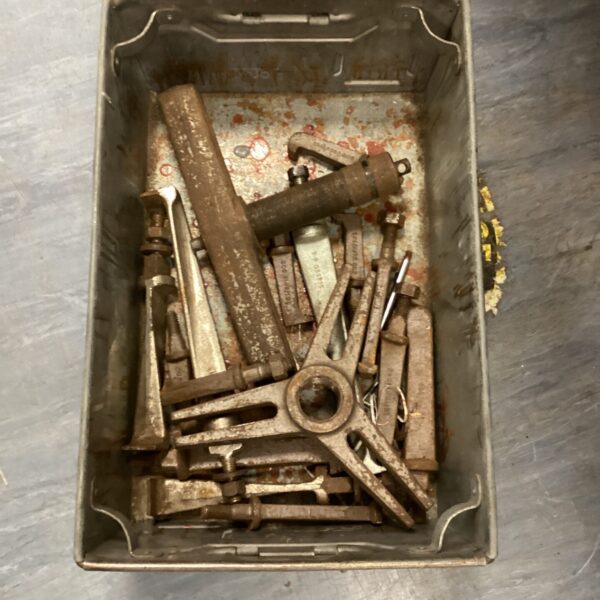 Vintage three legged puller tool showing rust and wear.