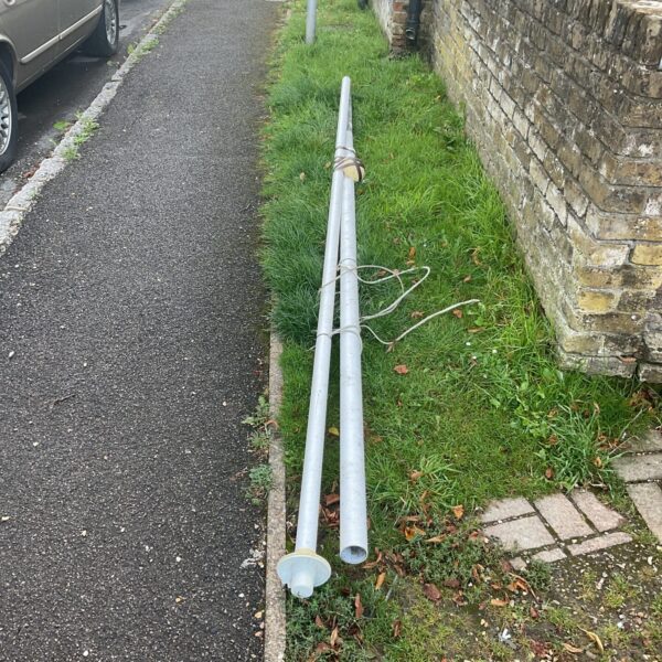 Metal flag pole sections in a garden setting.
