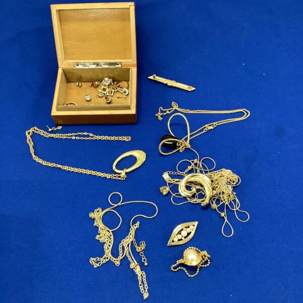 Open wooden box filled with vintage costume jewellery.