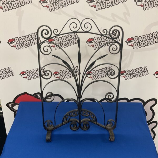 Antique wrought iron fire guard with elegant curves.
