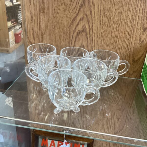 Six vintage cut glass tea cups displayed on a surface.