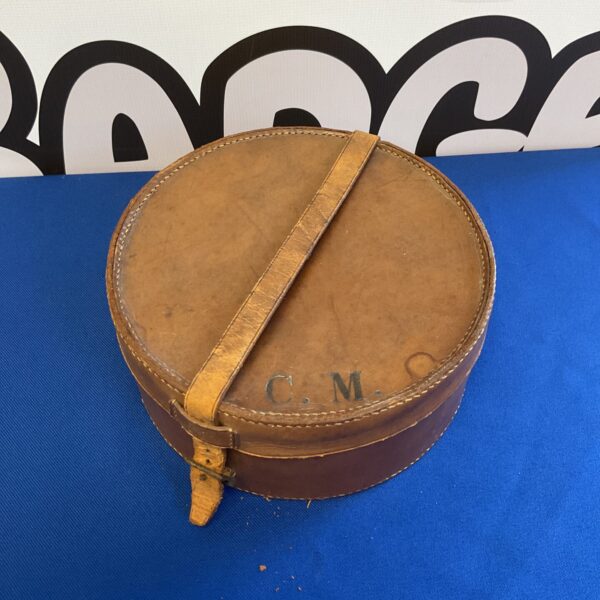Vintage leather hat box with buckle strap, antique travel accessory.