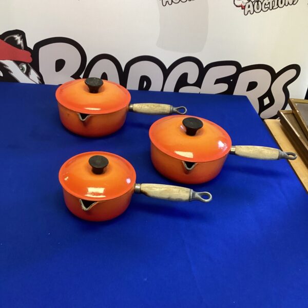 Vintage Le Creuset orange pans with lids in a lot.