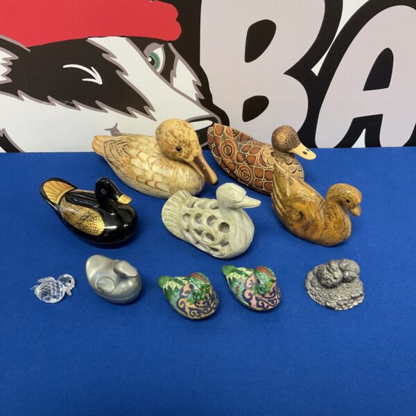 Collection of wooden, stone and crystal duck figurines.
