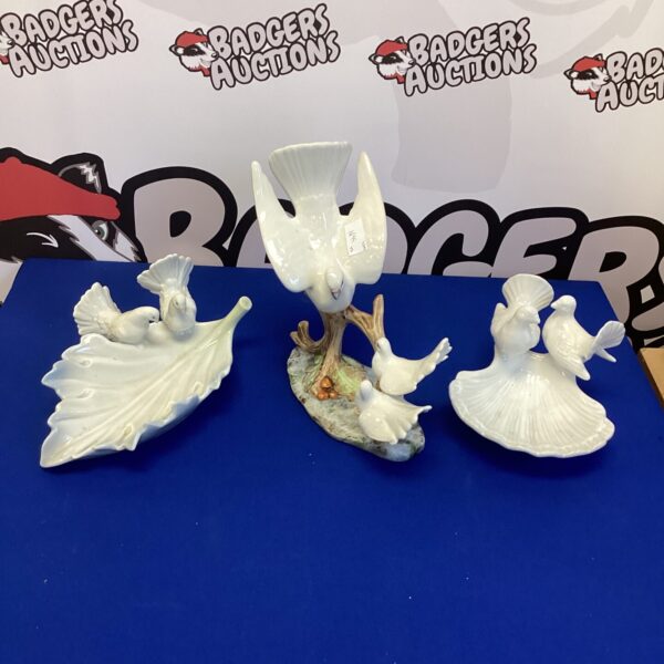 Vintage porcelain bird figurines displayed on a patterned surface.