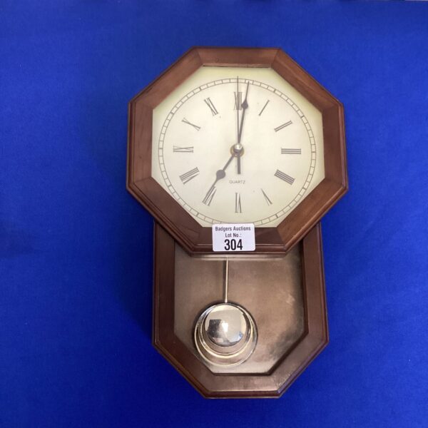 Vintage quartz pendulum clock with wooden case and swinging pendulum.