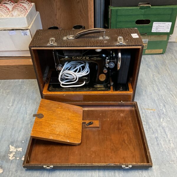 Vintage Singer sewing machine in wooden cabinet, antique collectible.