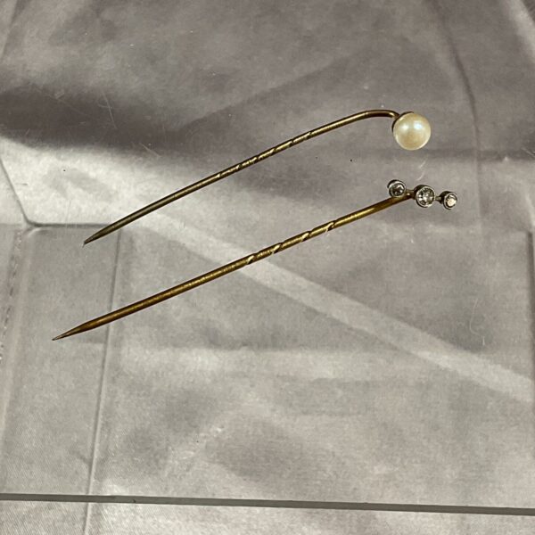Close-up of 9ct gold stick pins with pearl and diamond settings.