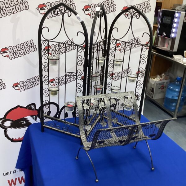 Ornate iron candle holder with log basket for rustic decor.