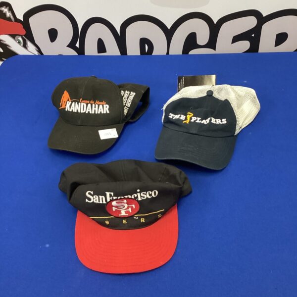 Baseball cap lot featuring PGA Tour, Coupe du Monde, and San Francisco 49ers branding.
