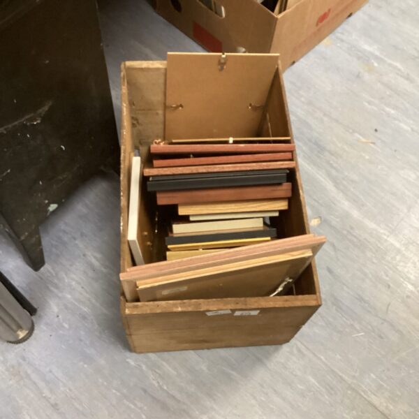 Assorted vintage wooden picture frames in a storage box.