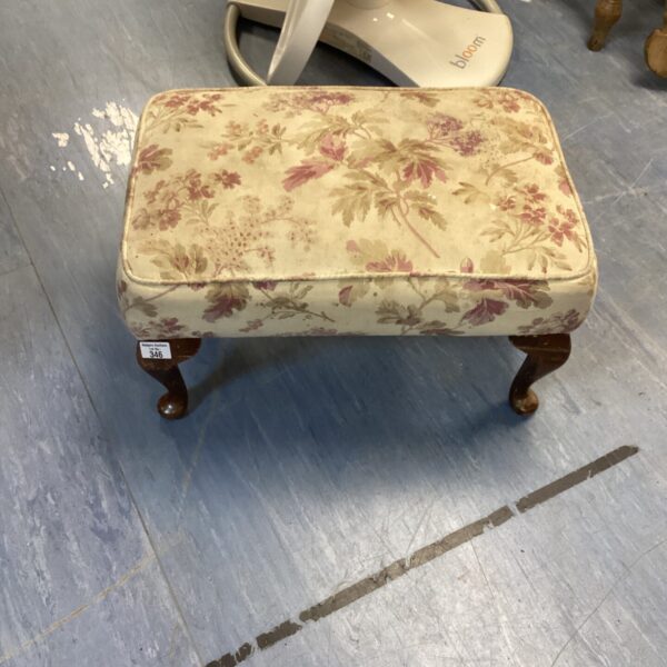 Vintage floral foot stool with turned legs and patterned upholstery.