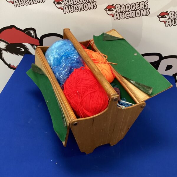 Vintage wooden sewing box filled with colourful wool and knitting needles.