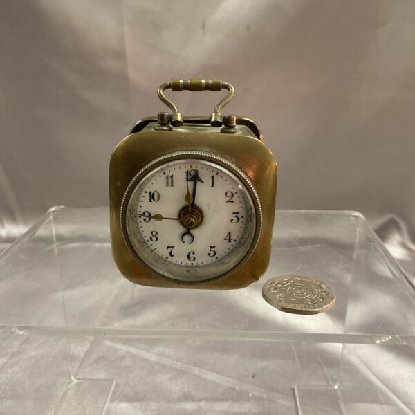 Vintage brass travel alarm clock showing the dial.