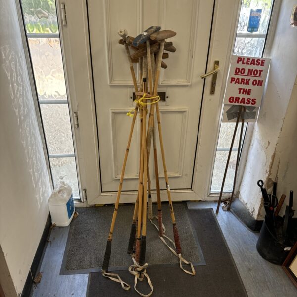 Vintage polo mallet set leaning against a wall.