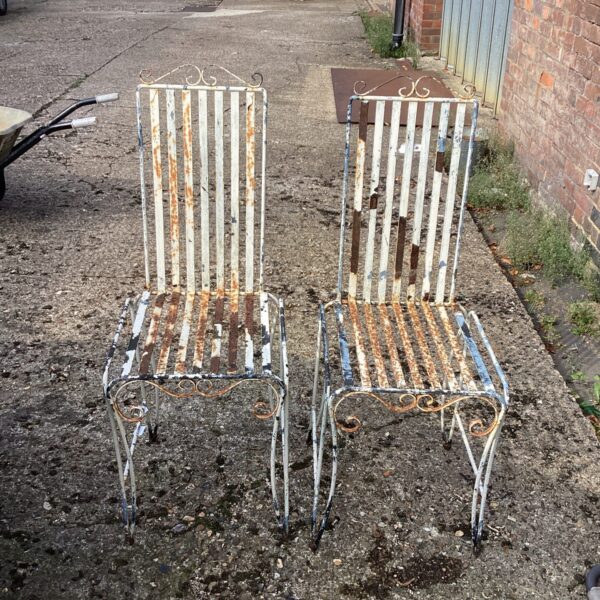 Rusted vintage metal garden chairs with slatted seats and backs.