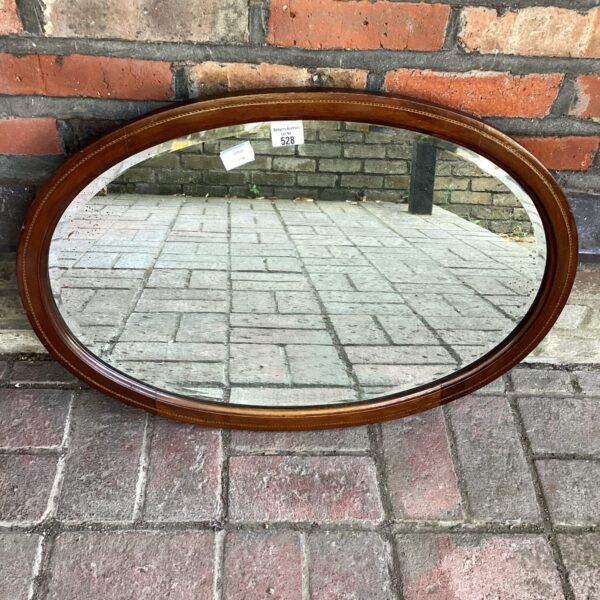 Antique mahogany oval mirror with inlaid detailing, vintage wall decor.