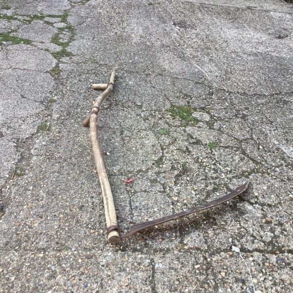 Vintage garden scythe with curved blade and wooden handle.