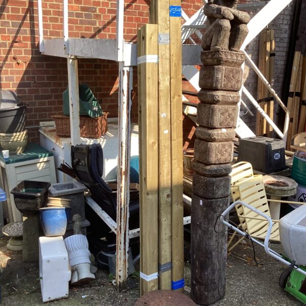 Intricate carved timber post in a garden setting.
