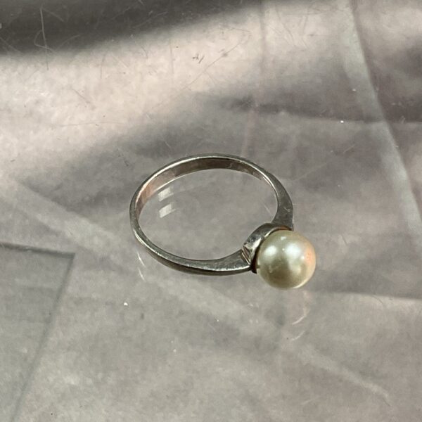 Close-up of a silver ring with a pearl.