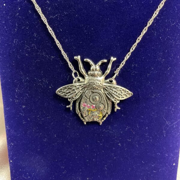 Close-up of a steampunk bee pendant with watch parts.
