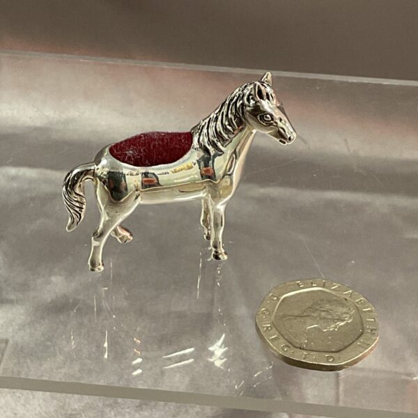 Antique silver horse pincushion with red velvet saddle.