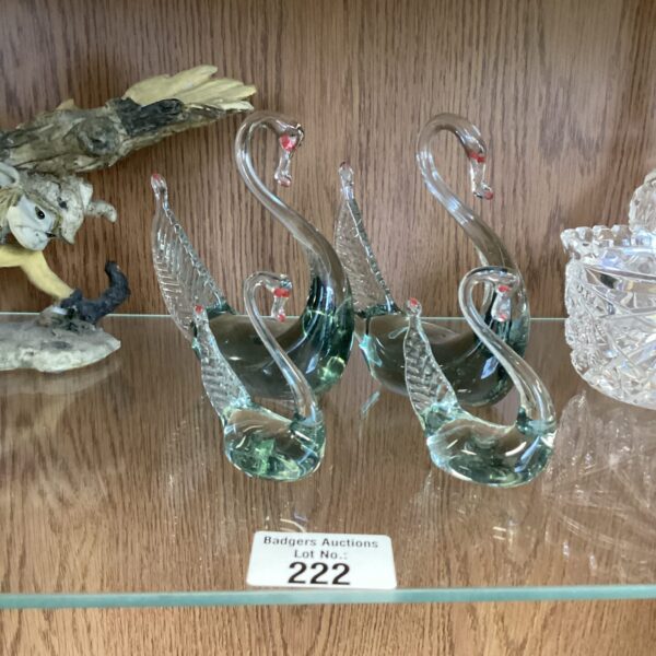 Group of four delicate Murano glass swans on a wooden surface.