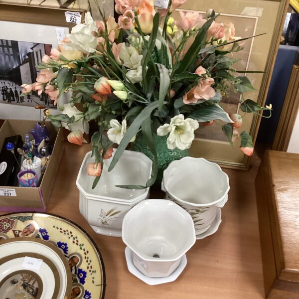 Ceramic plant pot holders with a jug of artificial flowers.