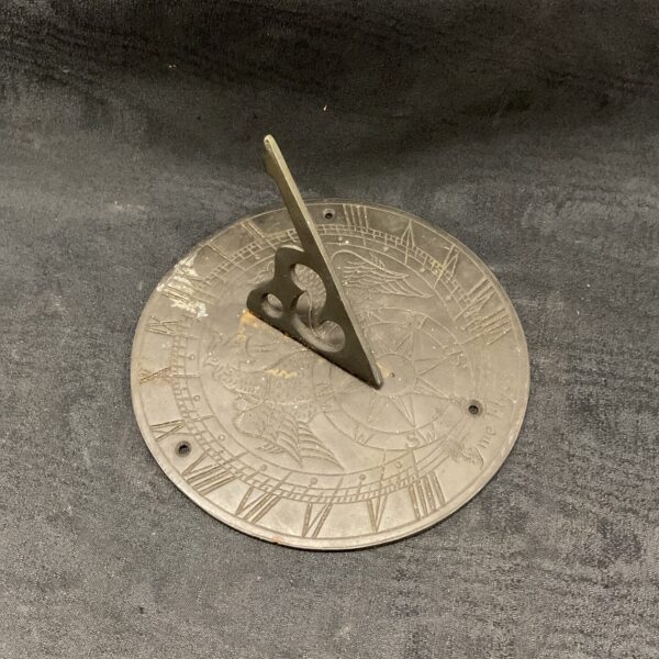 Antique brass sundial with "Tyme Flyes" inscription and griffon detail.