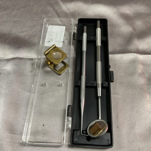 Vintage dental tool set in clear plastic case with magnifying glass.