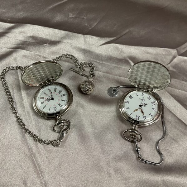 Close-up of a pair of vintage-style pocket watches with chains.