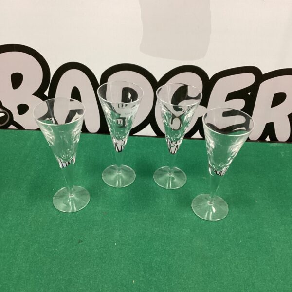 Four elegant modern cut glass wine glasses on a dark surface.